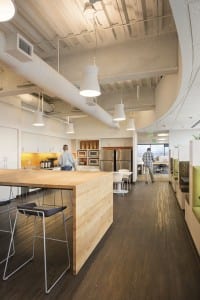 Break area’s exposed ceiling elements, butcher block tables, bench-style seating and concrete floors all pay homage to the company’s industrial heritage.